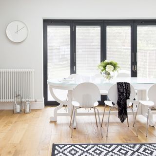 white dining room with glass dining table and wooden flooring