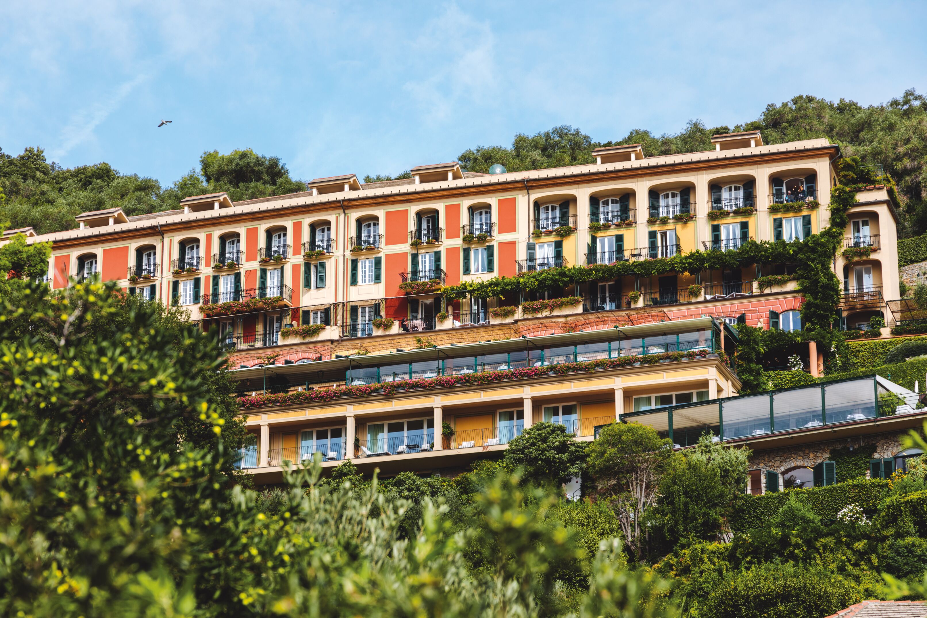 The dusty tomato and sunshine yellow facade of the Hotel Splendido set amidst the verdant greenery of Portofino