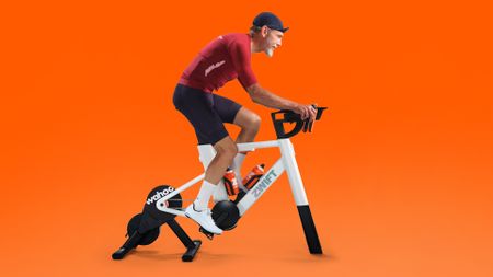 Man riding the Zwift Ride with KICKR CORE 2 on an orange backdrop