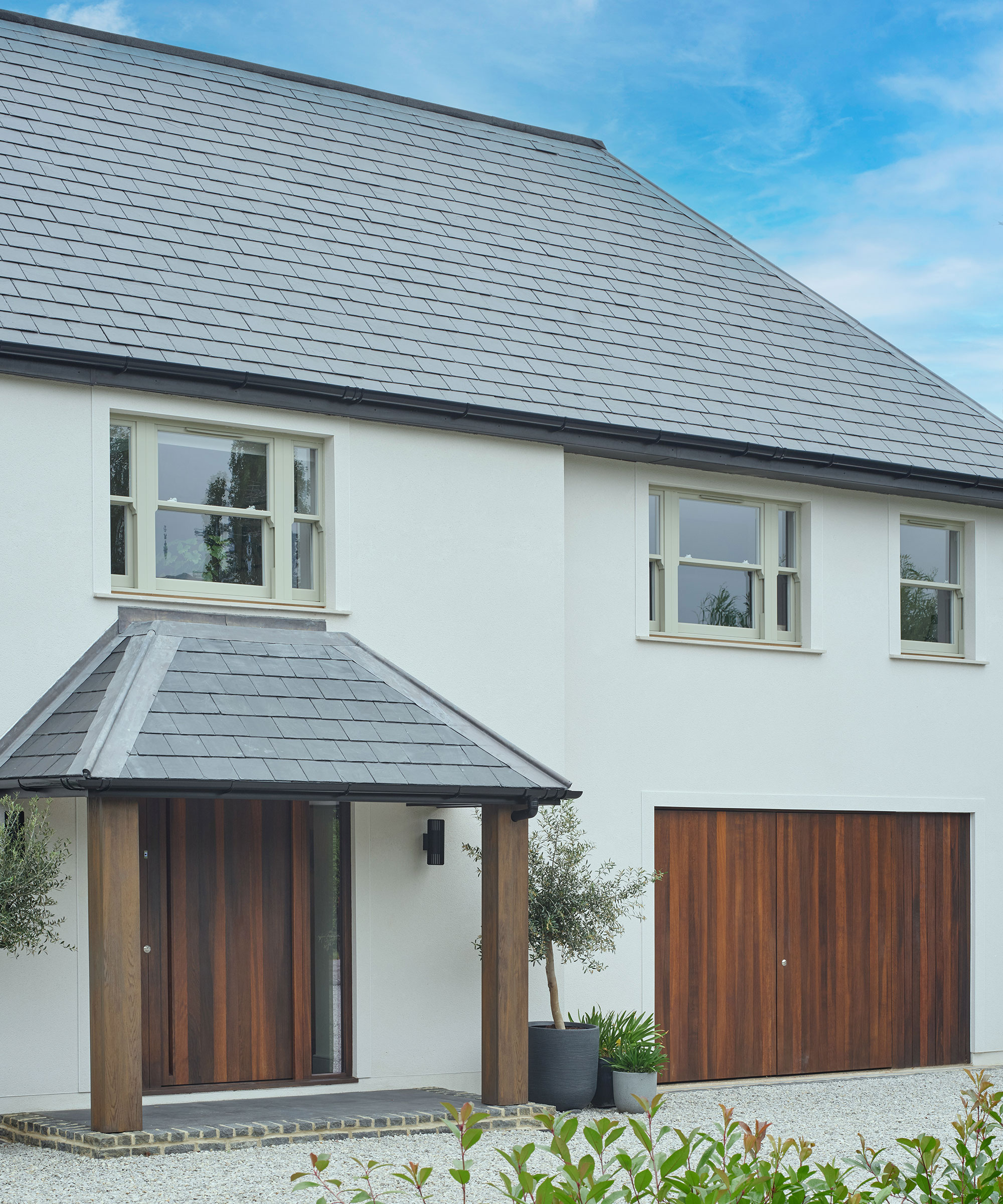 white rendered house with slate roof and painted sash windows and fumed oak front door and garage door