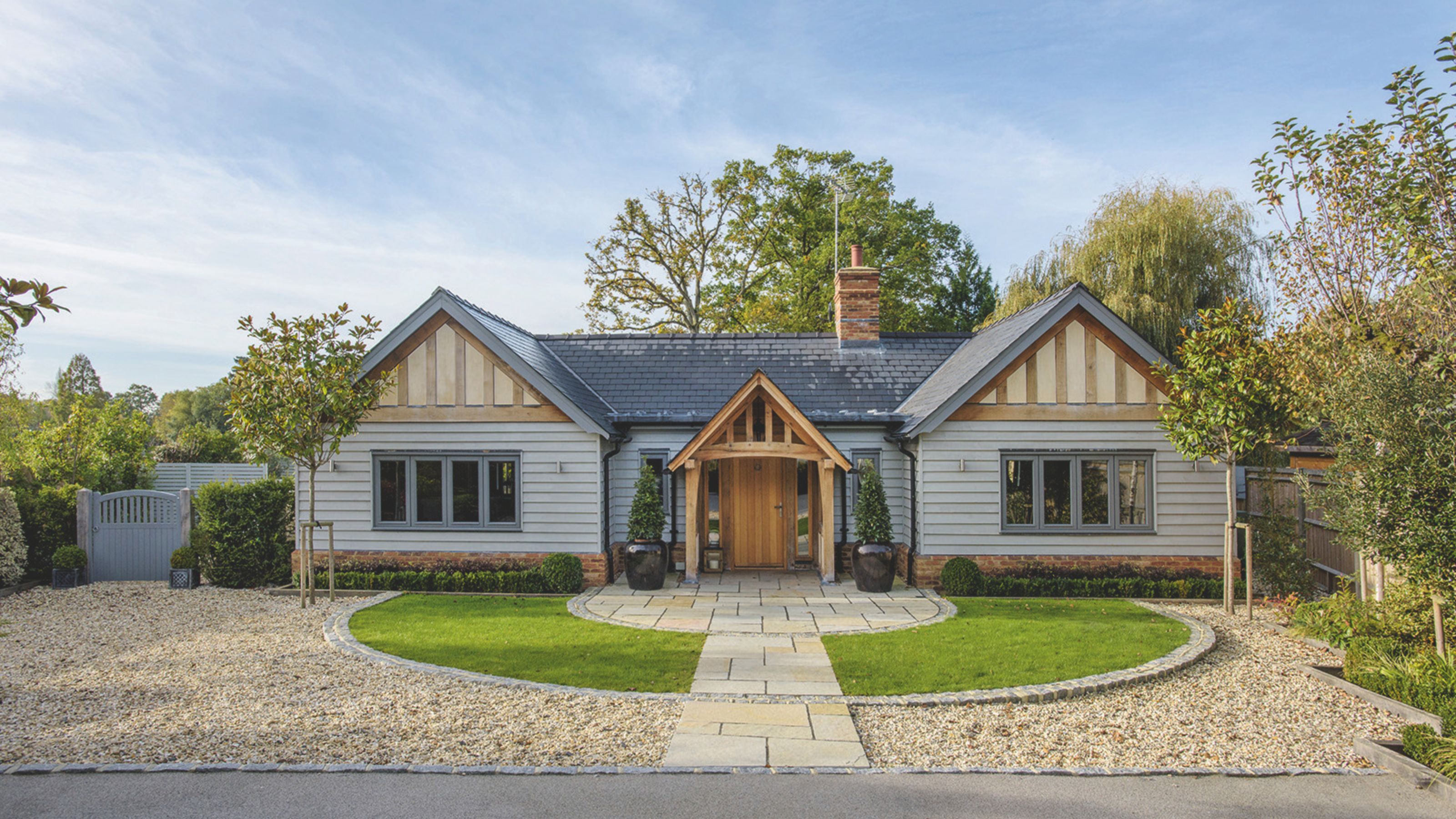 Oak frame and cladded bungalow with porch and beautiful gravel, grass and pathway in the front garden