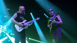 Killswitch Engage's Joel Stroetzel and Dutkiewicz rock their Caparison S-styles onstage. Fluoro green stage lights illuminate the dark.