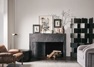 A black marble fireplace with an off-center firebox, all surrounded by an art-filled living room.