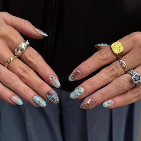 A picture of a woman's hands wearing lots of rings with blue and brown nail art