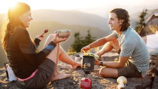 best camping stoves: A pair of campers enjoying a hot meal