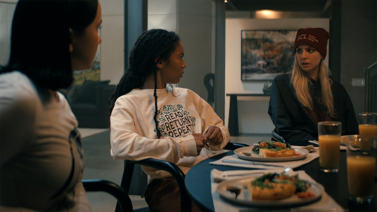Jordan and Marie looking at Cate as they sit at a table filled with food in Gen V season 2 episode 6