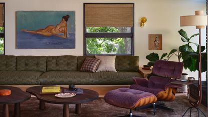 modern living room with bamboo blinds, timber ceiling, large green sofa, purple eames chair, floor lamp, fiddle leaf fig, nesting coffee tables, and gray-purple rug