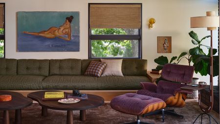 modern living room with bamboo blinds, timber ceiling, large green sofa, purple eames chair, floor lamp, fiddle leaf fig, nesting coffee tables, and gray-purple rug