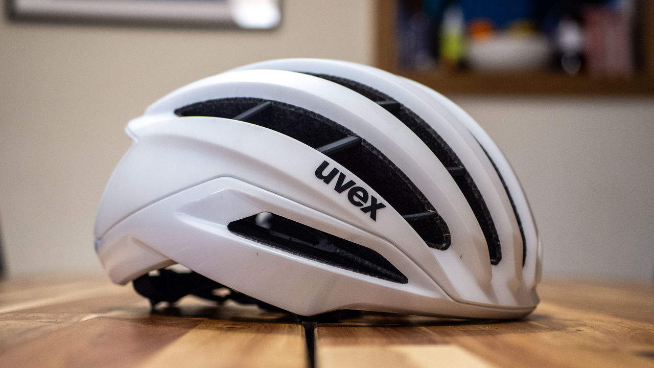 A white Uvex Surge helmet stands on a wooden table