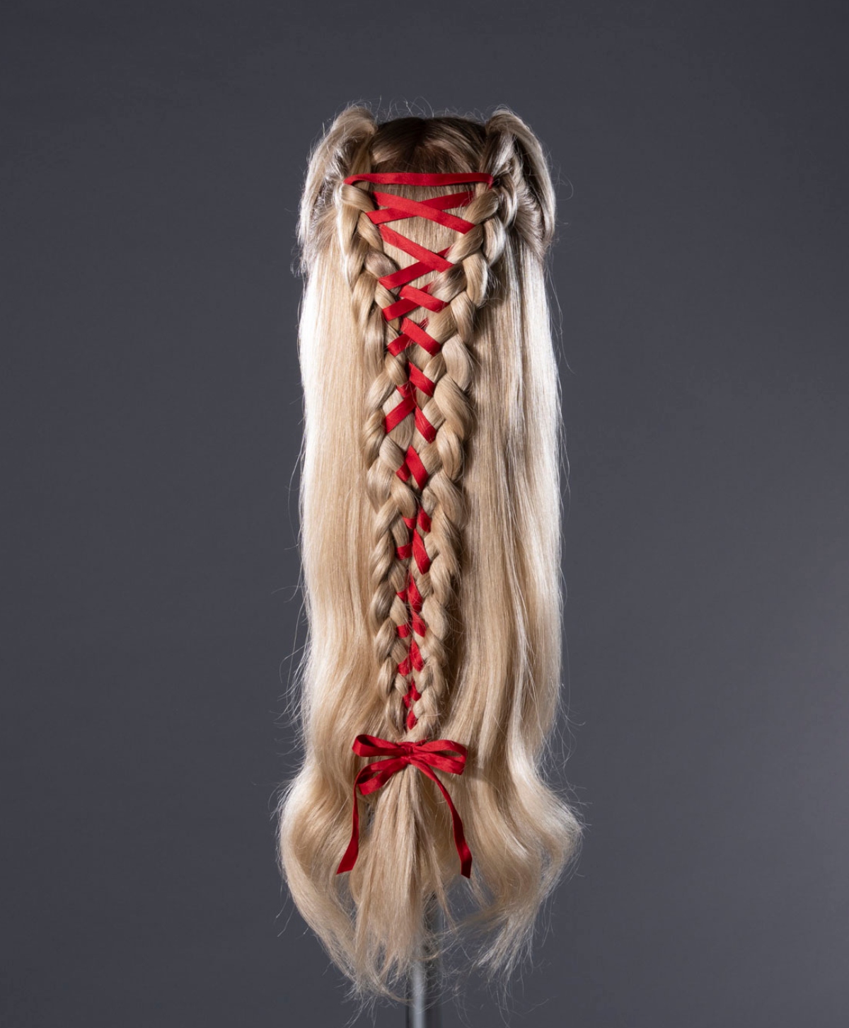 A blonde wig with braided details and criss-crossed red ribbon used on Margot Robbie As Catherine Earnshaw in "Wuthering Heights" (2026)