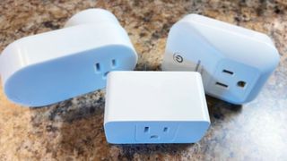 Three HomeKit smart plugs on a flat surface.