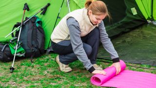 Woman rolling up sleeping pad outside tent