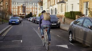 Person cycling on road wearing backpack