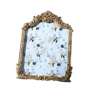 A brass vintage-style frame with a blue floral print in the middle of it