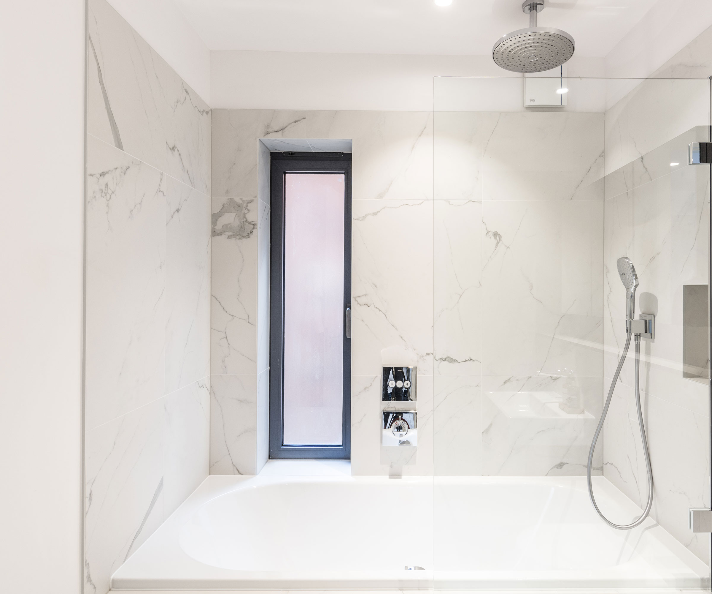 modern bathroom with marble effect shower panels and narrow vertical window with privacy glass