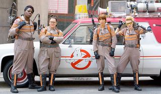 Ghostbusters 2016 lineup standing in front of the Ecto-Mobile