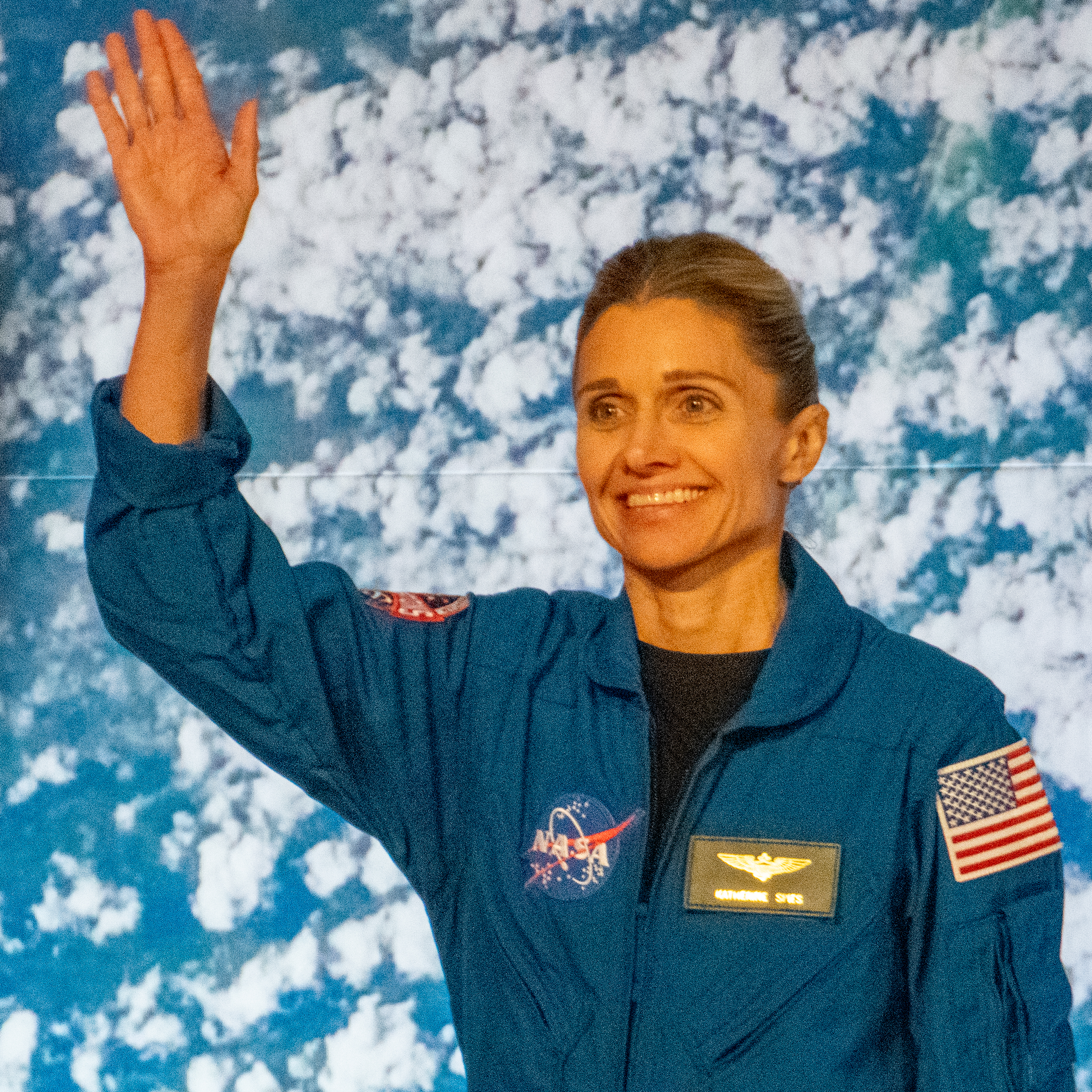 people in blue jumpsuits smile and wave.