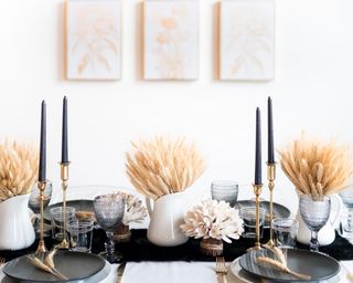 A monochromatic thanksgiving-themed dining table with dried wheat in white vases