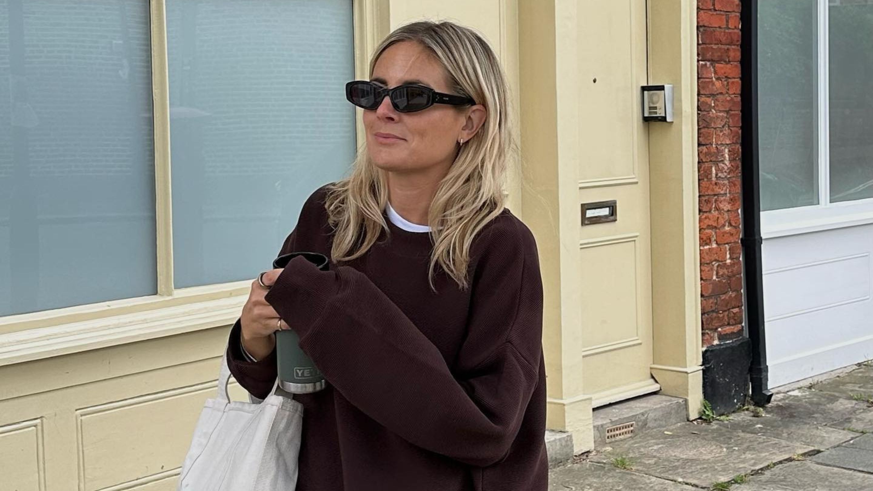 Influencer @lucywilliams02 stands outside in London wearing burgundy leggings with a burgundy jumper and black sunglasses.