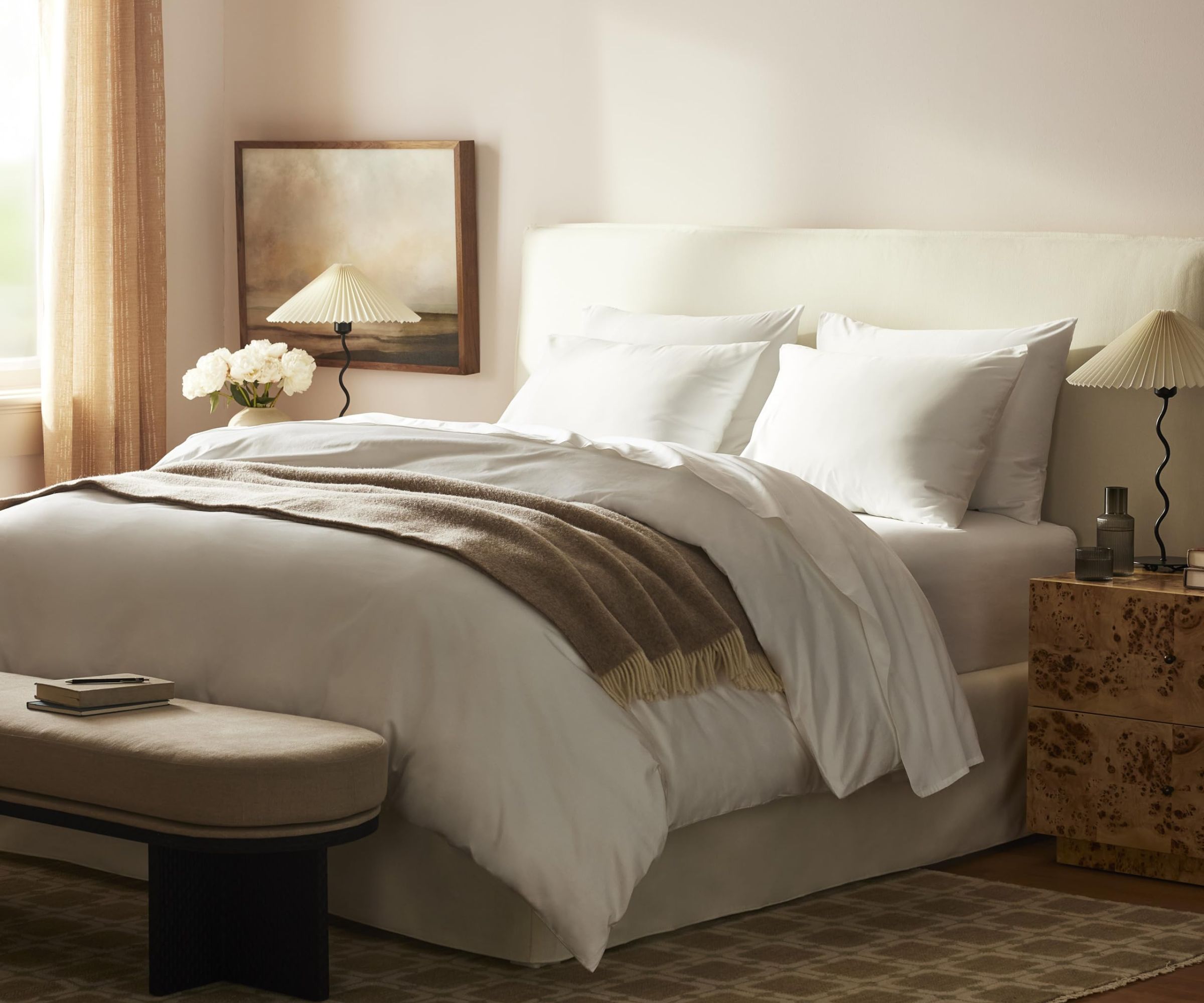 Brooklinen sateen sheets on a bed against cream walls.