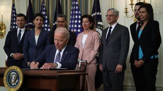 President Joe Biden signs executive order as (L-R) Secretary of Transportation Pete Buttigieg, Chairperson of the Federal Trade Commission Lina Khan, Secretary of Health and Human Services Xavier Becerra, Secretary of Commerce Gina Raimondo, Attorney General Merrick Garland, National Economic Council Director Brian Deese, and Acting Chairwoman of the Federal Communications Commission Jessica Rosenworcel look on during an event at the State Dining Room of the White House July 9, 2021 in Washington, DC. 