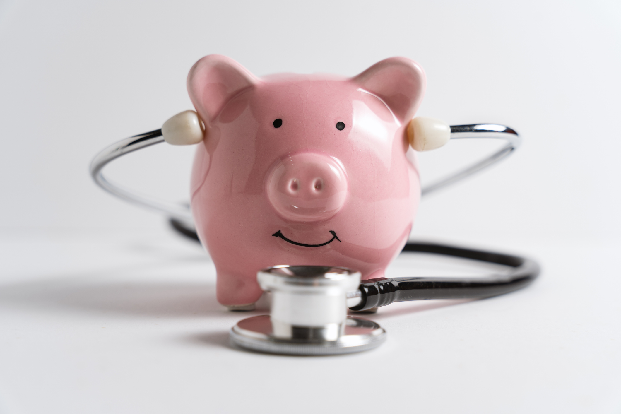 A pink piggy bank with a stethoscope wrapped around it, symbolizing financial health and savings.