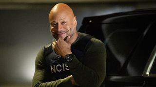 LL Cool J puts a hand on his chin while he smiles at the camera in an NCIS vest during big Sam Hanna return episode.
