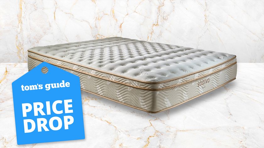 Image shows the Saatva Classic mattress on a white and rose gold marble background with a blue Presidents&#039; Day mattress sales luggage tag badge overlaid on the bottom left hand corner