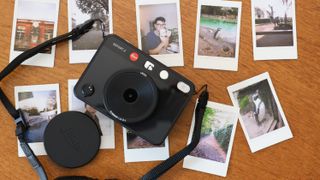 Leica Sofort 2 camera surrounded by Instax Mini prints