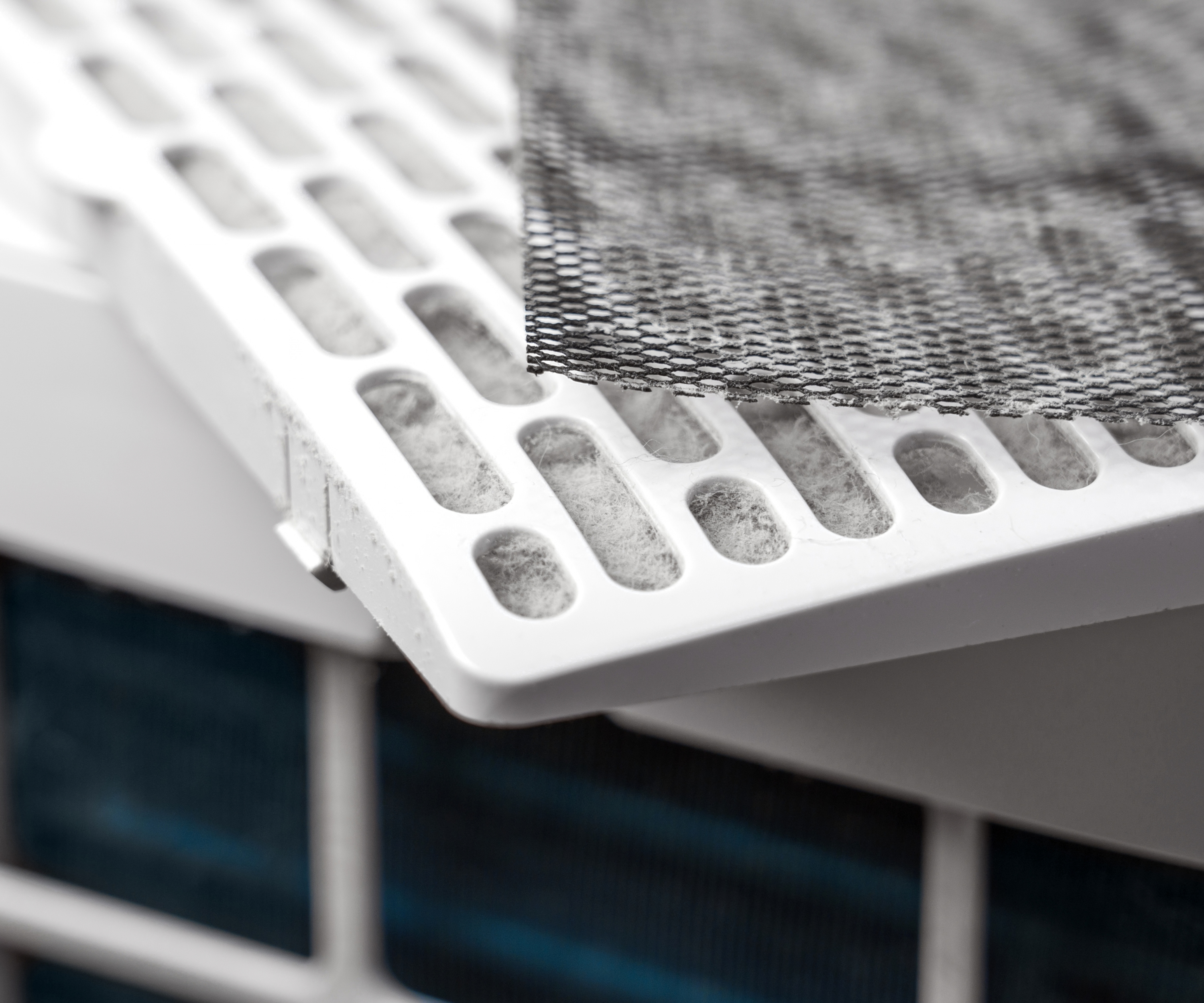 Disassembled air purifier with used mesh filter on dusty plastic white cartridge closeup