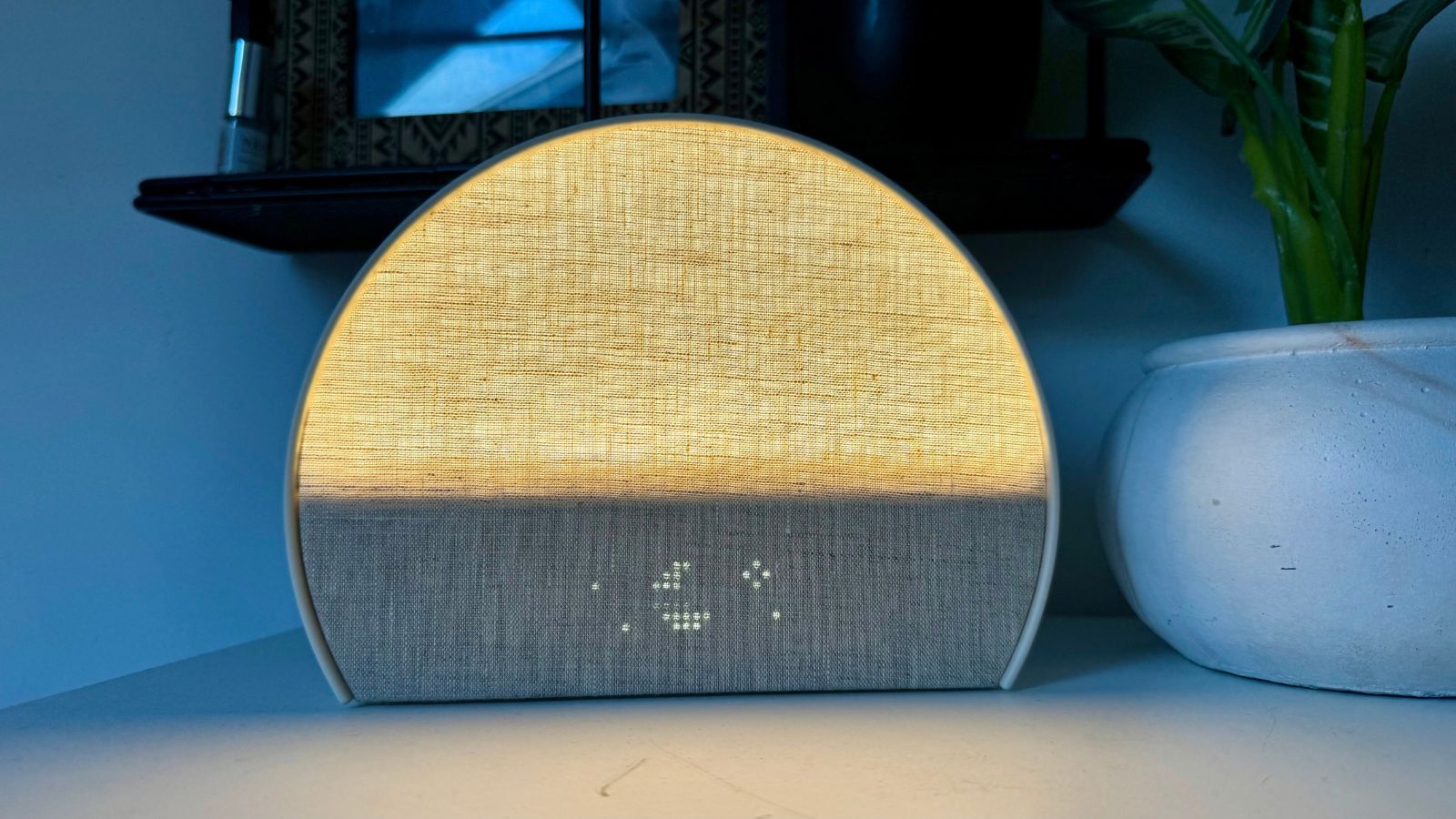Beige Hatch Sleep Clock on white surface lighting up with warm light