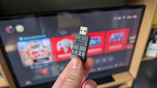 8bitdo wireless adapter in front of TV with switch 2 home screen