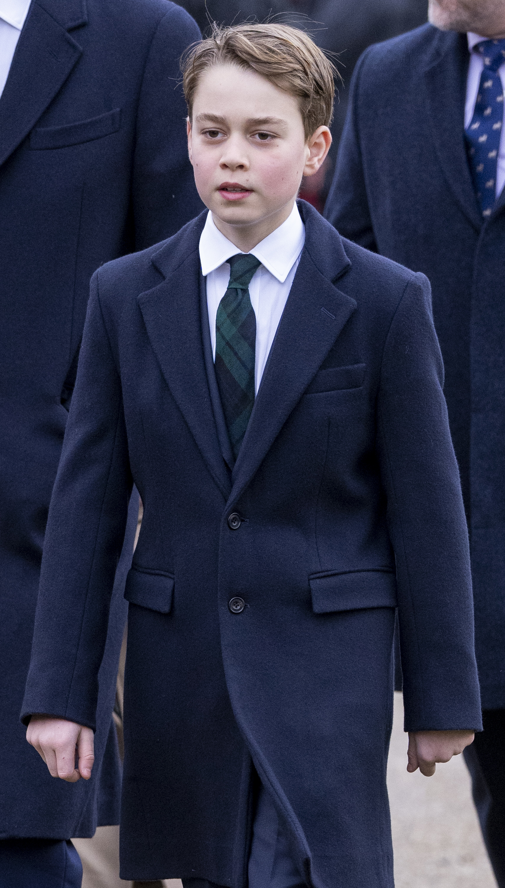 Prince George looks serious while wearing a navy suit and white shirt and has his hair combed to one side