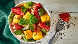Bowl of fruit salad with mango and strawberries and poppy seeds