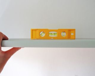 using a spirit level to check the shelf is level
