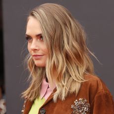 Cara Delevingne wears a brown suede jacket