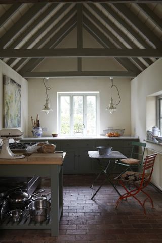 green and white kitchen in period property with green painted units and green painted beams vaulted ceiling terracotta tiles