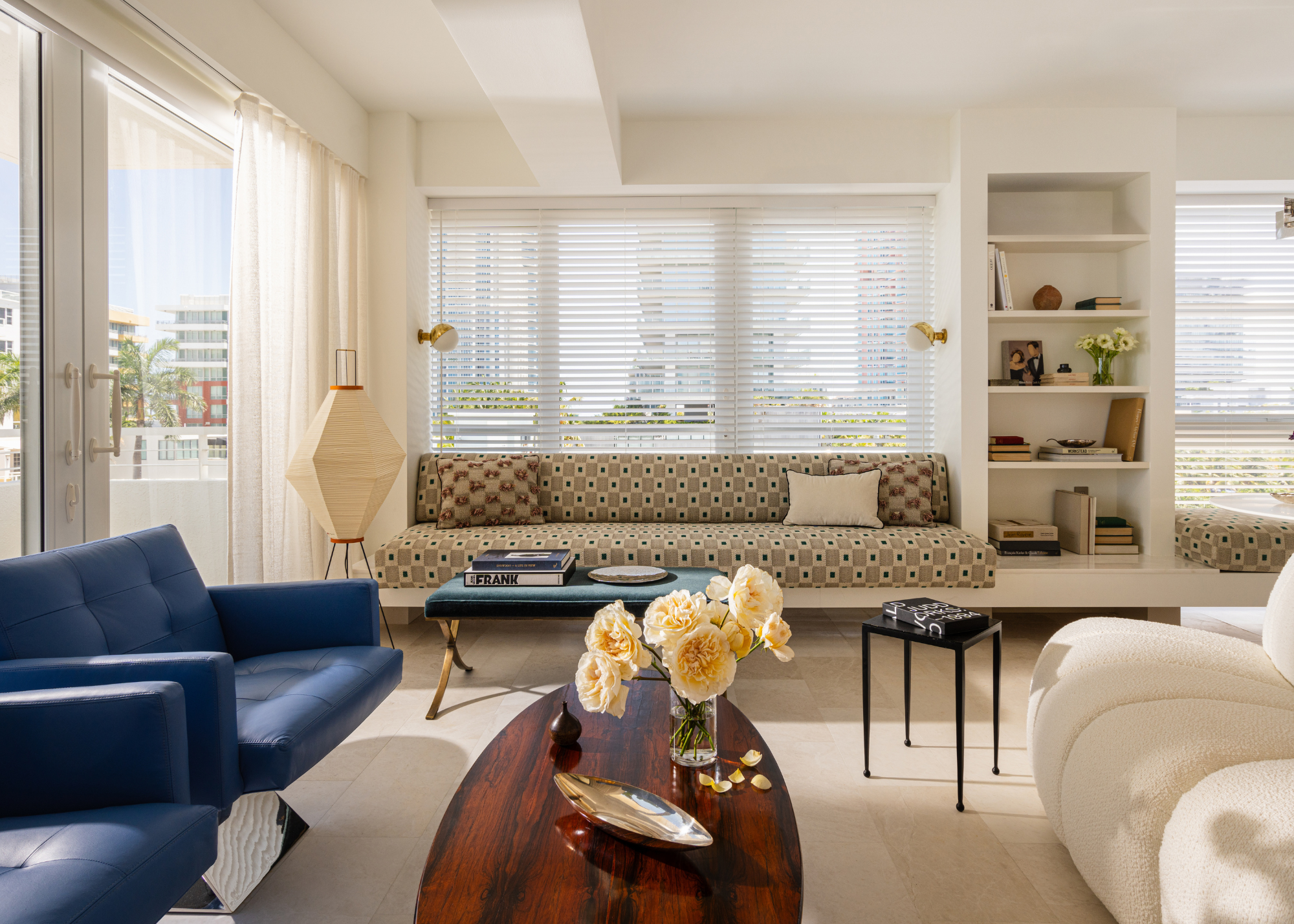 modern living room with low furniture an akari light, blinds, and built-in shelving