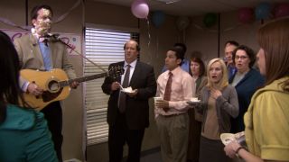 Andy holding the guitar with cake on his face in The Office