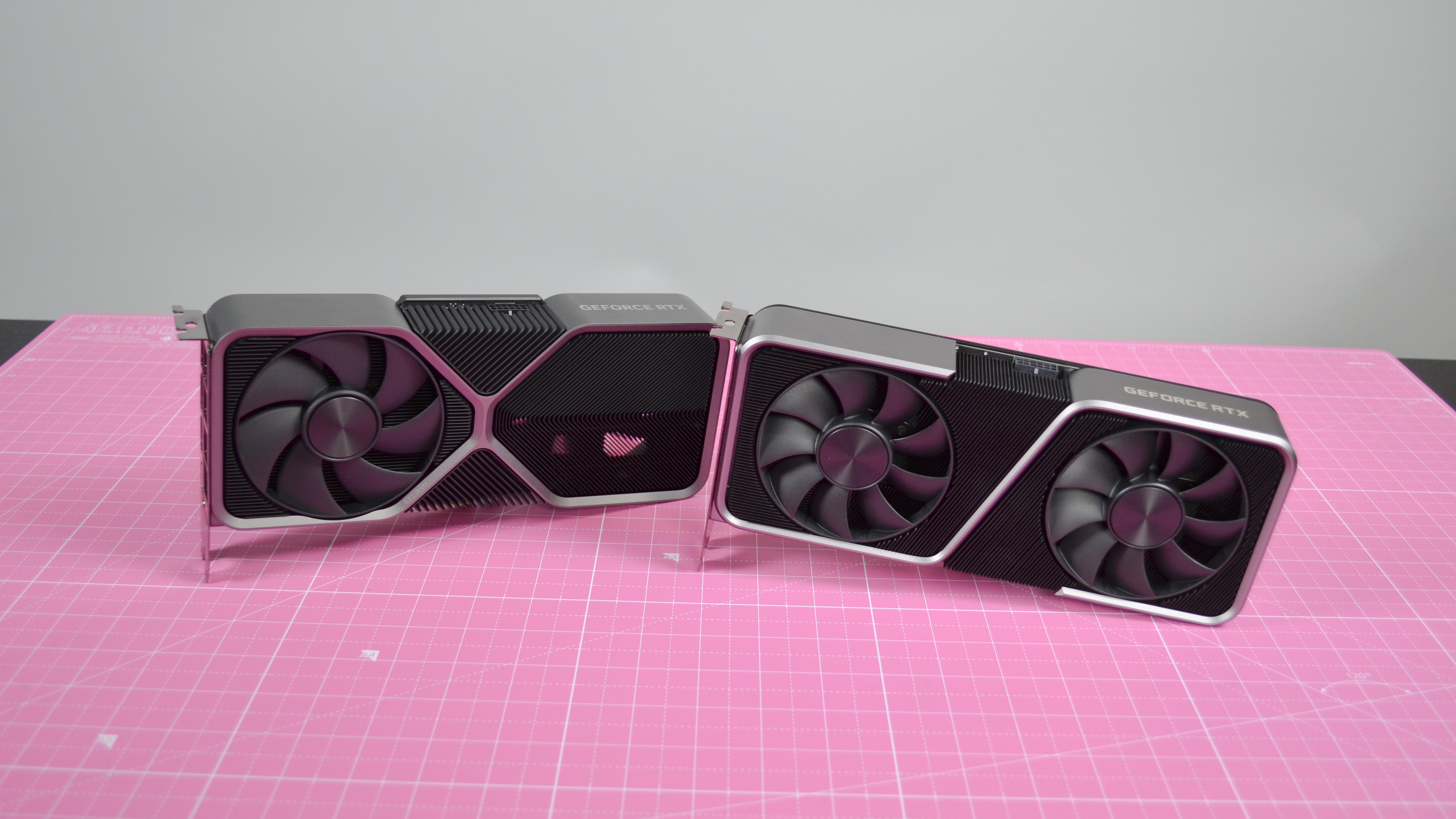 La NVIDIA RTX 4070 y la RTX 3070 una al lado de la otra, sobre una superficie rosa