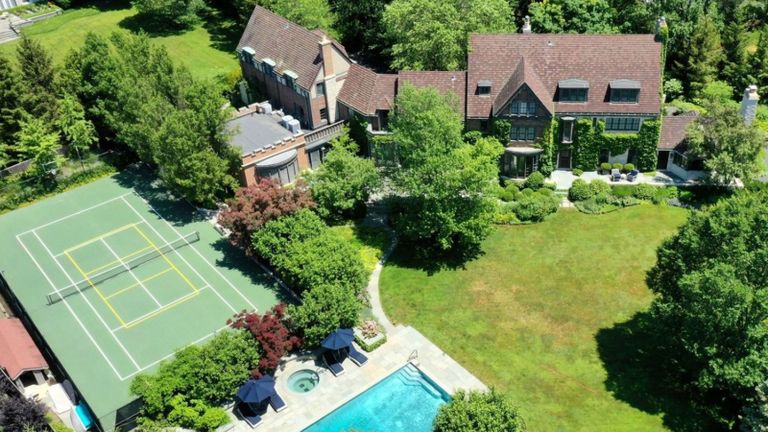 Birdseye view of green tennis court next to arts and crafts style house