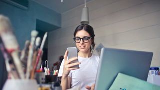 A woman using a smartphone and laptop.