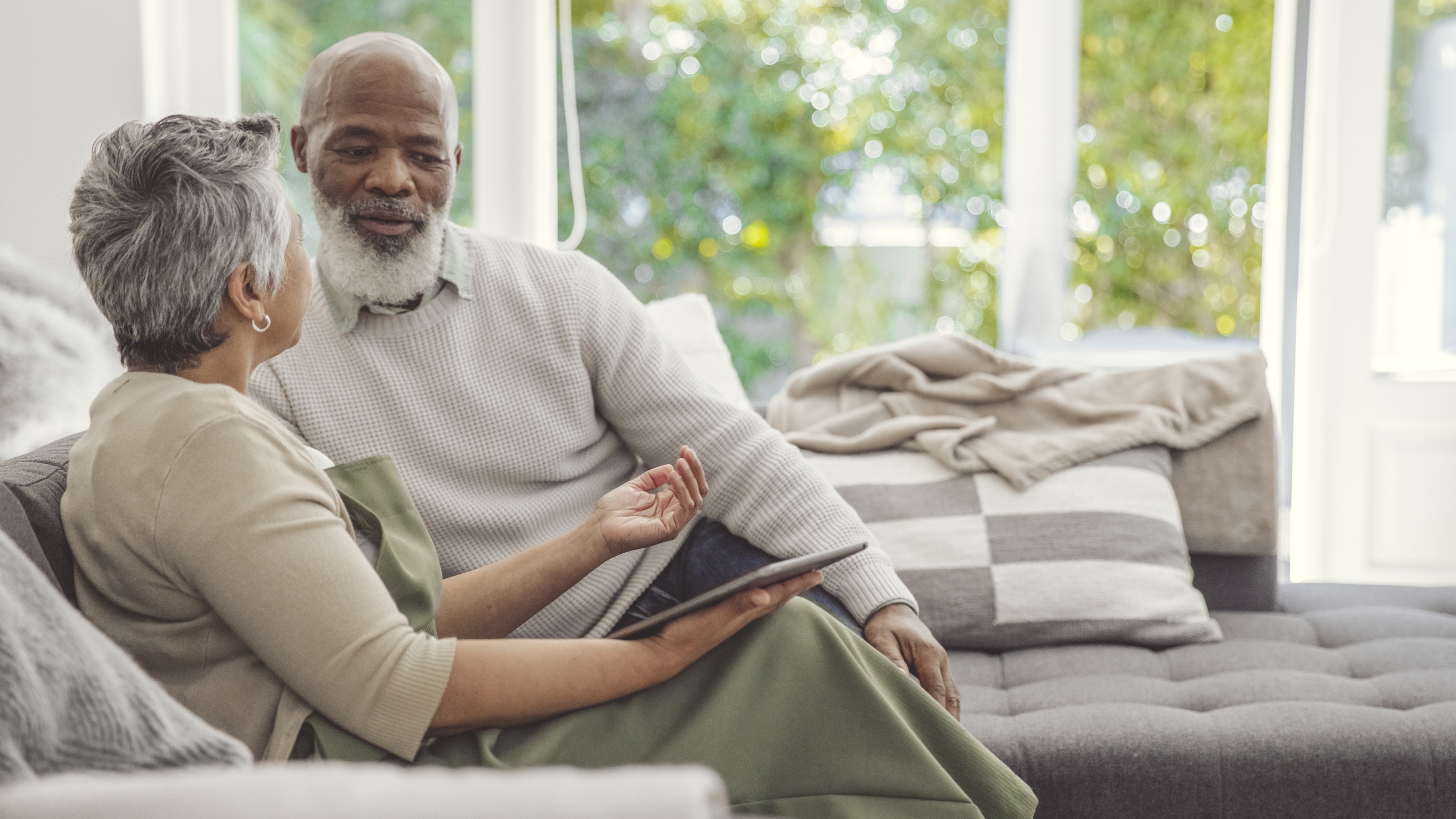 An older couple look relaxed on the sofa together.