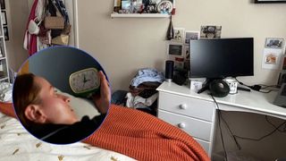 The image shows a cluttered bedroom, with clothes piled on the floor and bags hanging off of the door. There is a desk with a laptop at the foot of the bed. Inset, a woman wakes up and check the clock - it's 3 a.m.