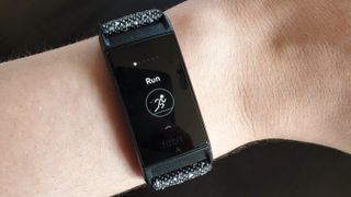 Fitbit Charge 4 med svart armband på en persons handled.