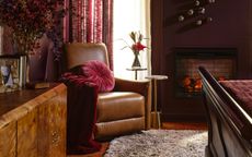 A bedroom with brown walls, a burl wood credenza, and a leather armchair in the corner