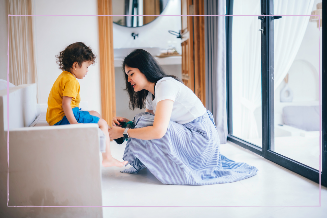 Mother putting on toddler&#039;s shoes while trying to leave the house