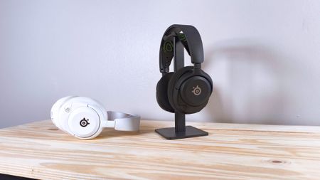 Two pairs of the SteelSeries Arctis Nova 5X in black and white on a wood table