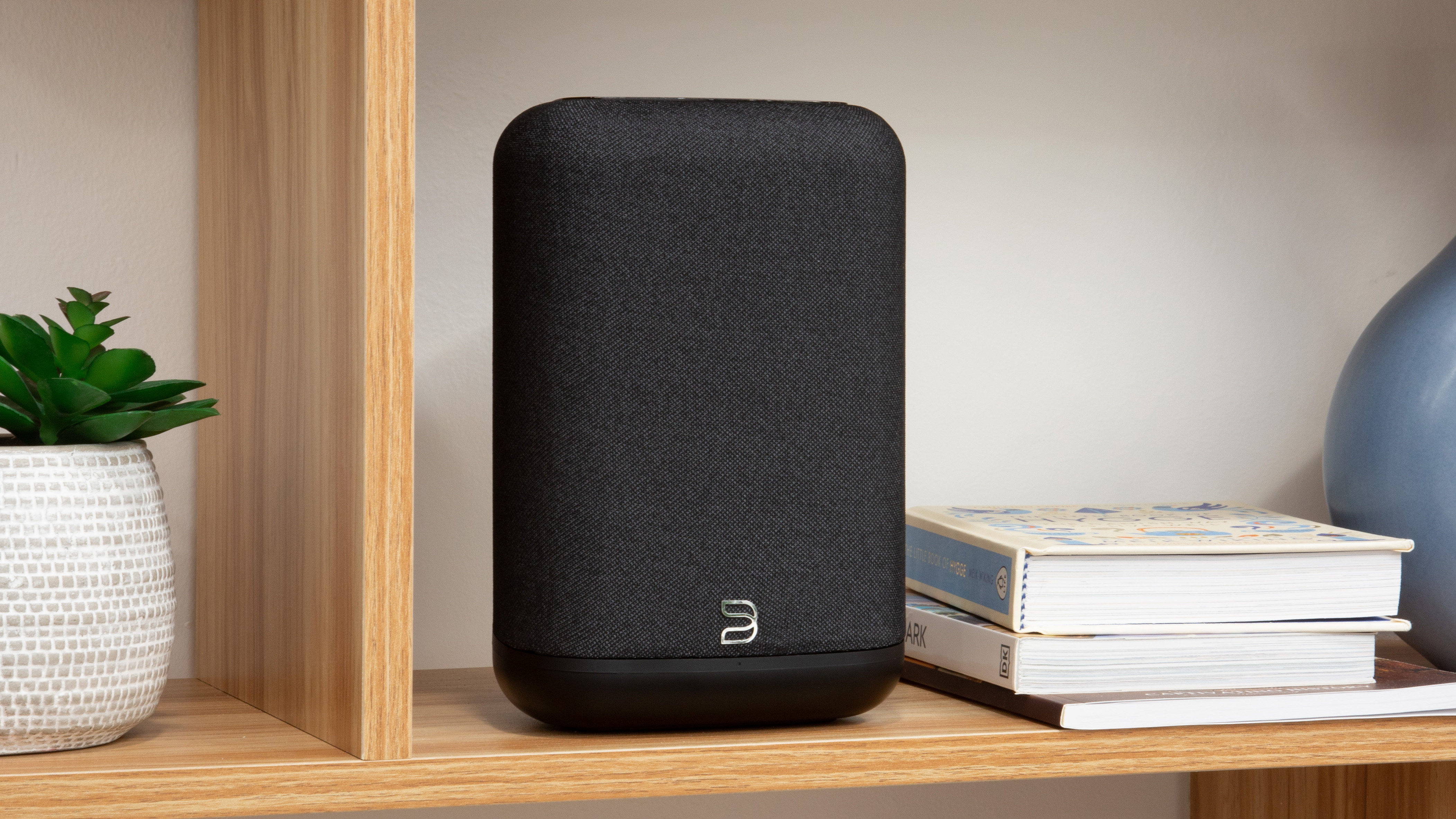 The Bluesound Pulse Flex in black on a wooden shelf