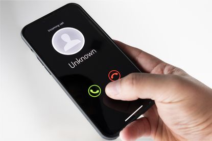 Hand holding a mobile showing incoming unknown call